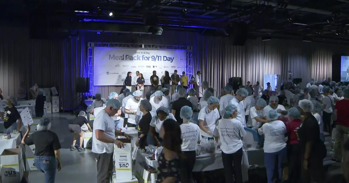 Hundreds of volunteers in hairnets packing meal kits at the New York City Meal Pack for 9/11 Day
