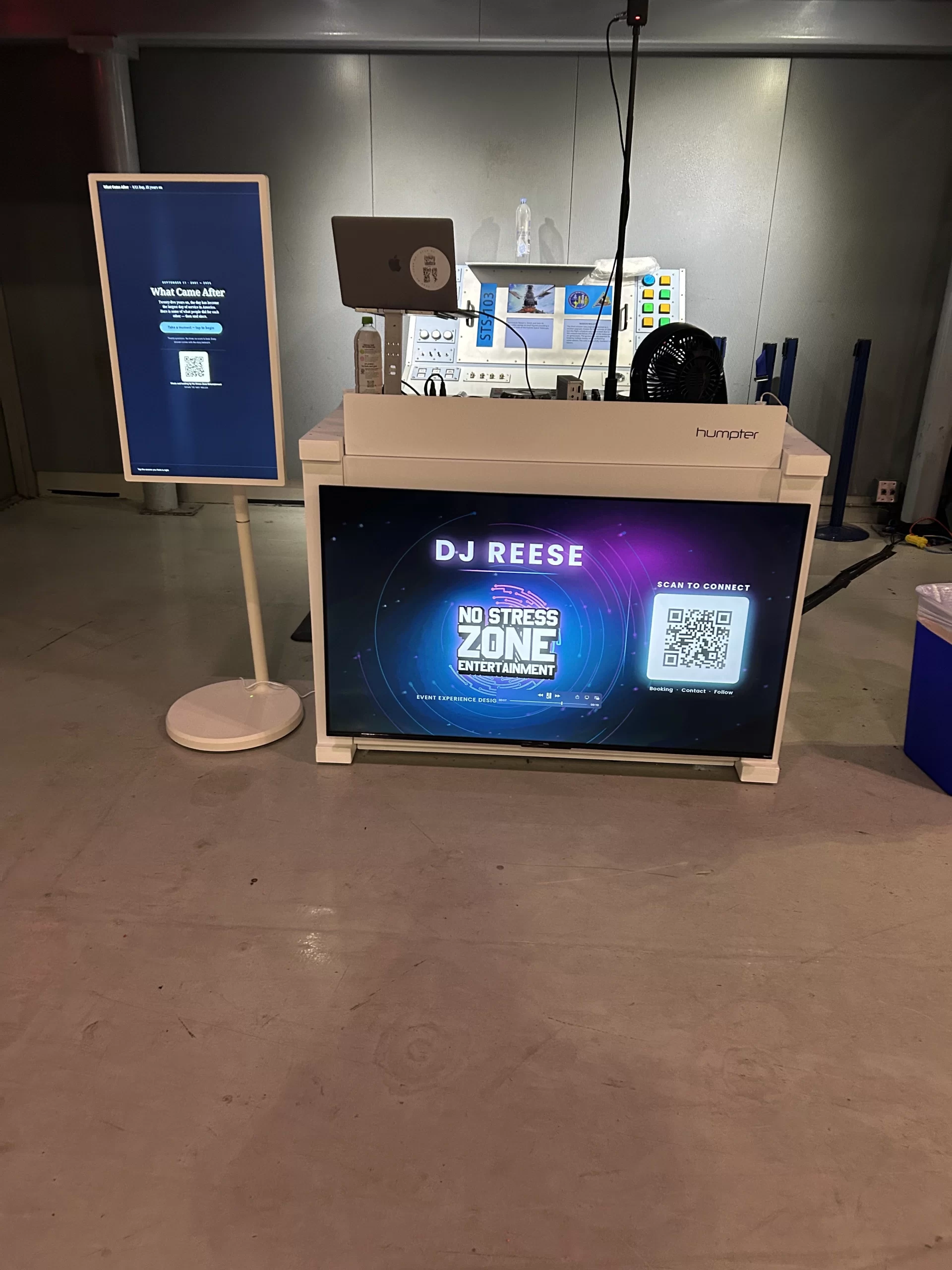 Vertical touchscreen kiosk showing a trivia question next to a DJ booth with a branded front screen and a QR code reading scan to connect