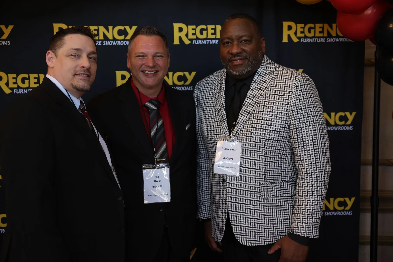 RMS team members posing in front of the Regency Furniture Showrooms backdrop
